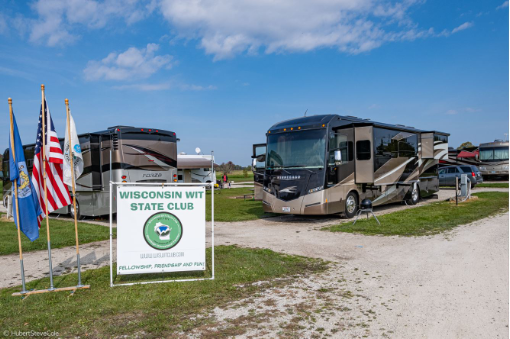 Two Winnebago motorhomes parked in campsites with Wisconsin WIT State Club Sign in the grass.